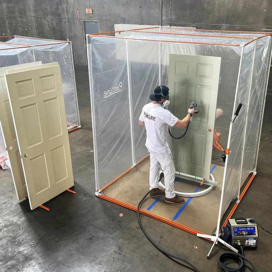 Painter painting a door inside Portable portable paint booth