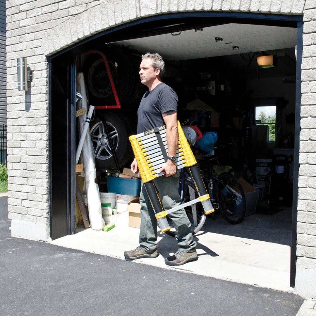 Man carrying a folded Metaltech telescopic ladder out of a garage
